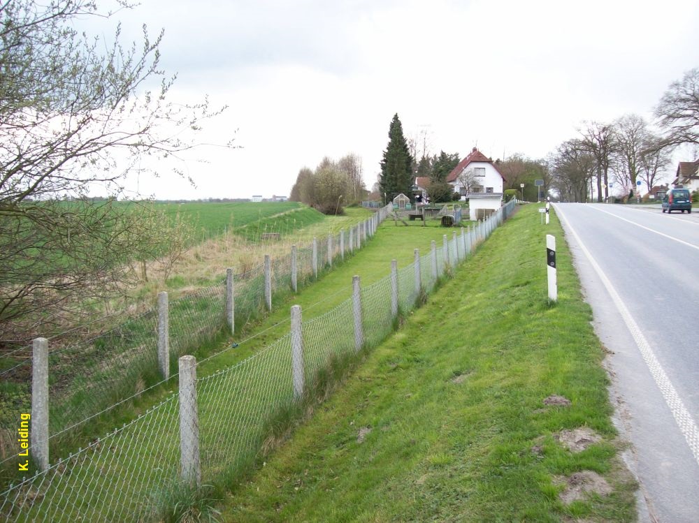 Verlauf der ehemaligen Bahnstrecke links vom Maschendrahtzaun zum Bahnhof *Holstendorf.