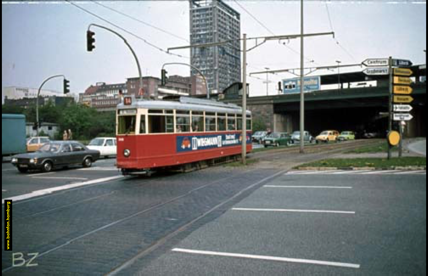 Die Straßenbahn fährt los, links von ihr ein Schwarm von Autos.